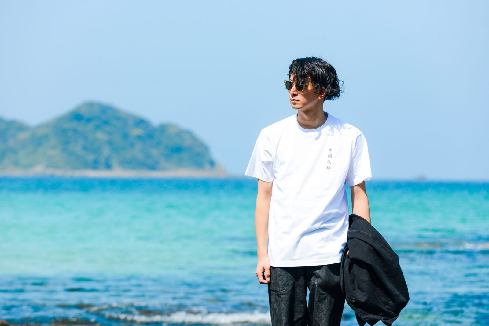 白Tシャツを着て海辺に立つ男性