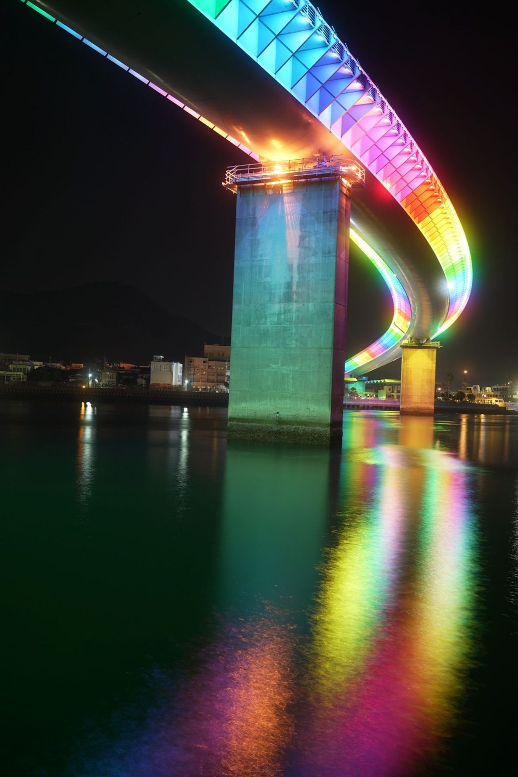 夜に虹色に光る橋と水面の映り込み