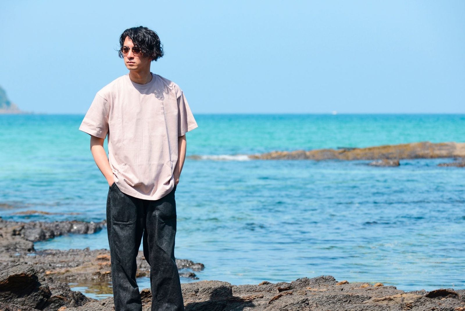 ピンクのTシャツで岩場に立つ男性