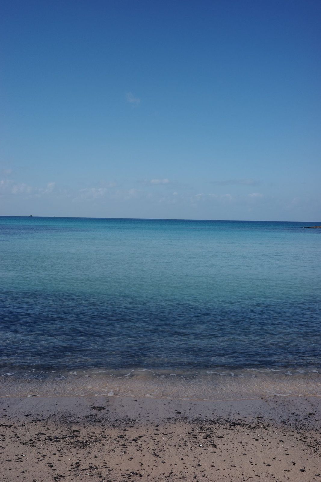砂浜から見るエメラルド色の遠浅の海